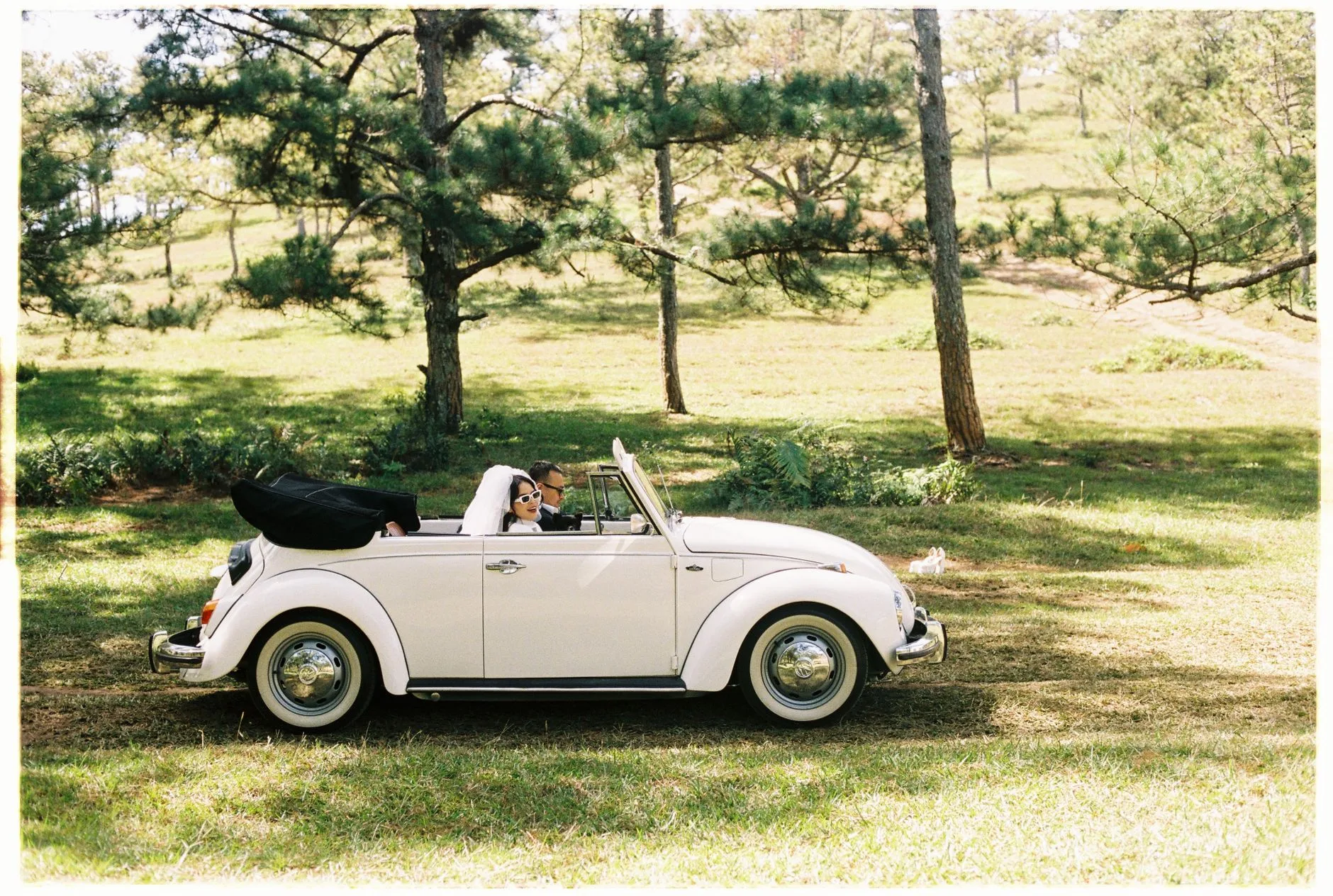White convertible decorated with ribbon parked outside a wedding venue.